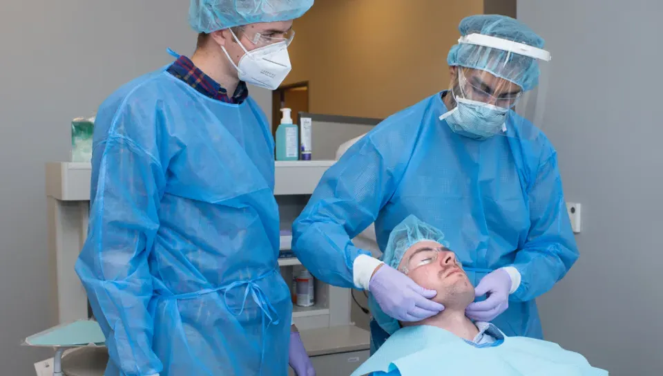 A physician assistant student assists a dental medicine student in giving a patient an exam as part of interprofessional education